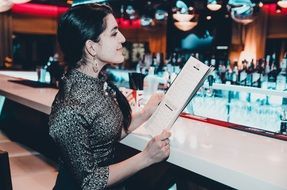 the girl behind the bar with a menu