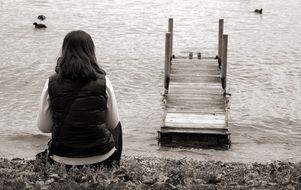 black and white photo of a girl resting on a lake