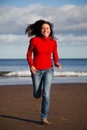 happy woman running along the beach