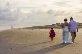 couple in love with a child walks along the beach