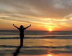 silhouette of a girl on the seashore during sunset