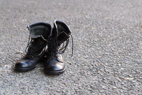 pair of black army boots on the pavement