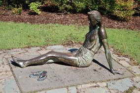 bronze sculpture of a woman sitting without shoes
