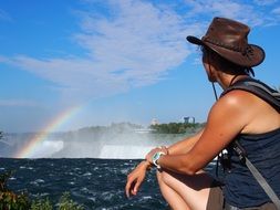 woman looking at rainbow above niagra falls, canada, ontario