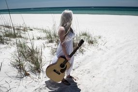 Blonde woman with guitar on sand Sea beach