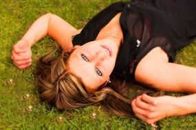 woman relaxing on green grass