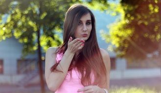 girl in a pink dress blows a kiss