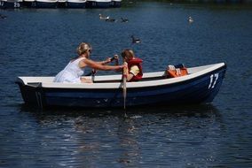 a woman with a child in a rowing boat on the lake