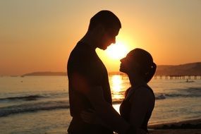 lovers look at each other on a golden sunset background