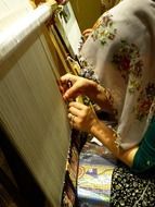 woman is weaving a carpet