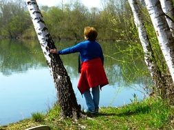 woman near birch by the lake on a sunny day