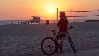 cyclist on the beach at sunset