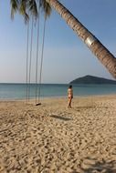 woman under palm tree on tropical beach