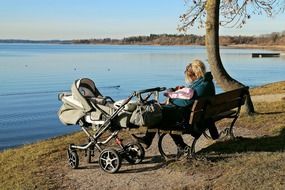 Mom is sitting near the lake with her baby