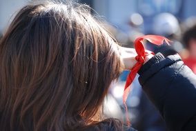 woman with long hair with a red ribbon on hand