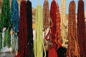 necklaces of different colors are hanging in the market