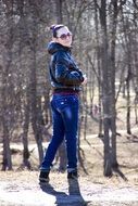 young girl in jeans strolls in park at autumn