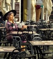 figure woman drinking tea at a table in a cafe