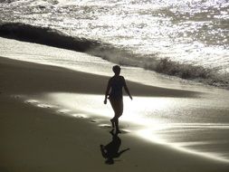 Woman is walking on the beach near the water