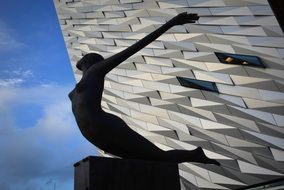 contemporary statue of a woman, building and blue sky with white clouds