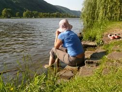 girl sitting on a stone near the river