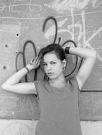Black and white photo of a girl posing on a graffiti background