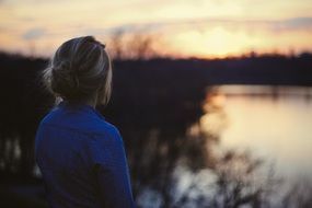 girl looks at the sunset over the lake