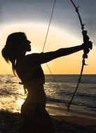 young woman with bow at sea, silhouette in back light