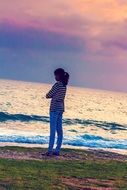 young woman near the water on a background of pink cloudy sky