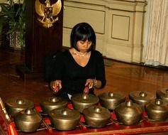 Woman is playing on the gamelan musical instrument