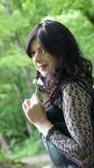 woman with a flower in hand on forest background