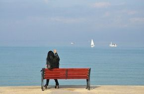 girl is sitting on a bench by the ocean in Andalusia