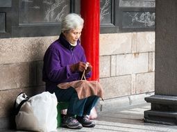 Asian elderly grandmother knitting on the street