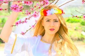 portrait of a beautiful girl with blond hair on the background of flowering tree branches in spring