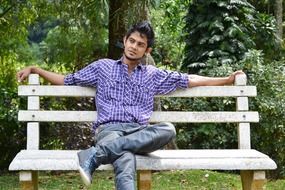 young man on a bench on the background of nature