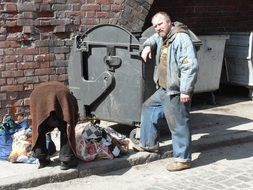 homeless couple near a garbage container in poland