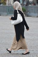 Woman dressed up in hijab walking on the pavement