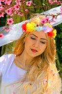 portrait of a beautiful blonde girl on background of blossoming branches of tree