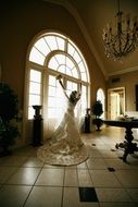 joyful bride in luxury gown at window