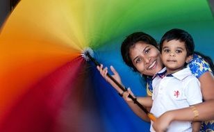 happy mom with a baby under a rainbow umbrella