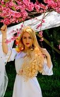 Girl with blond hair on the background of a flowering tree
