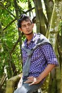 a young man leaned against a tree