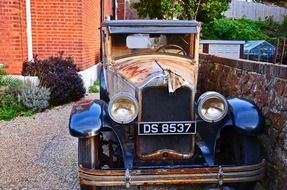 vintage car parked at stone fence