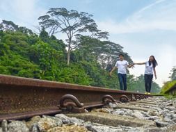 Asian couple walking on the railroad tracks