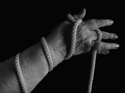 Hand holding a rope on black background