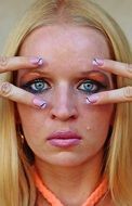 portrait of a girl with makeup on her face and fingers near her eyes