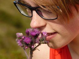 girl smelling thistle flower