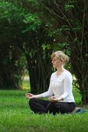 portrait of girl who is sitting on the grass in meditation