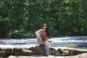 woman sitting on a stone near the river
