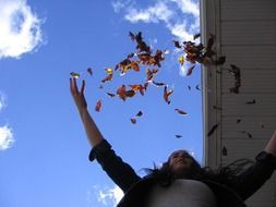 woman throws autumn leaves